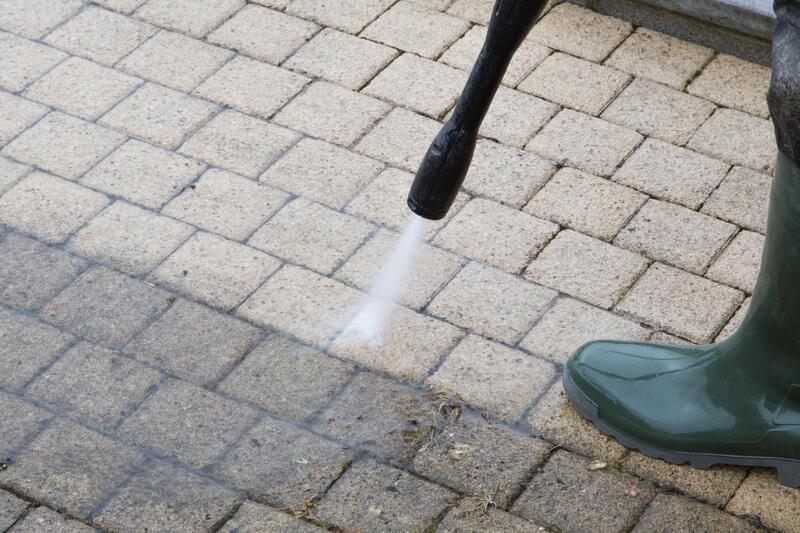 cleaning the driveway using pressure washer